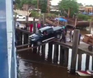 Caricano un'automobile sulla nave usando due pedane di legno