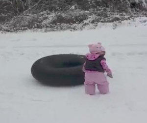 La bambina non sa scivolare sulla neve, qualcuno le mostra come si fa