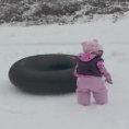 La bambina non sa scivolare sulla neve, qualcuno le mostra come si fa