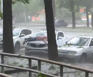 Donna russa protegge l'auto dalla grandine col proprio corpo